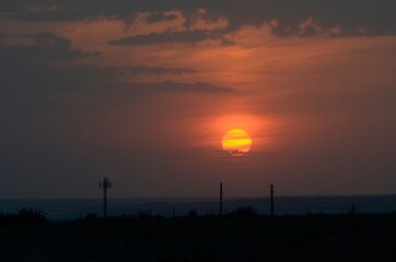 The antenna is a cellular transmitter and a line of wires against the backdrop of a pink sunset and a blue sky.