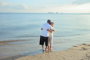 Fototapeta na wymiar Asian couple senior elder retire resting embrace at sunset beach honeymoon