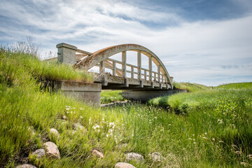 Fototapeta na wymiar The old lichen-covered concrete bridge in Cadillac, SK with green grass in foreground