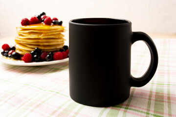 Black coffee mug mockup with pancakes and berries
