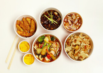 Chinese restaurant delivery food in paper container with wooden chopsticks. Isolated on white background. Top view.
