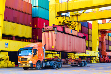 Container loading to a vessel, Quay crane pick up a container from trailer load onto a large container ship at a seaport. Container handling, transportation, and shipping.