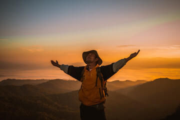 Fototapeta premium Men are climbing in the shadows in the sunset mountains, with backpacks on the top of the mountain, looking at the beautiful sky scenery, freedom concept.