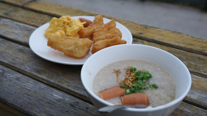 Minced Pork Porridge in white bowl with youtiao – fired dough Asian style breakfast on timber table