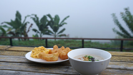 Minced Pork Porridge in white bowl with youtiao – fired dough Asian style breakfast on timber table