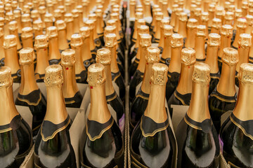 bottle of champagne and lots of rows of bottles with Golden caps. preparation for a holiday or...