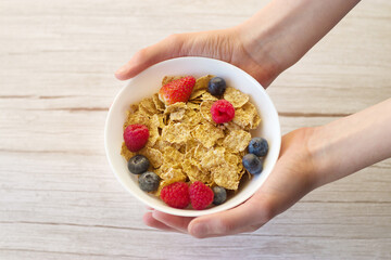 Healthy breakfast. Flakes and berries in a deep white plate in the hands