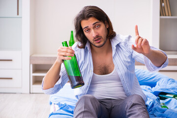 Young male alcoholic in the bedroom