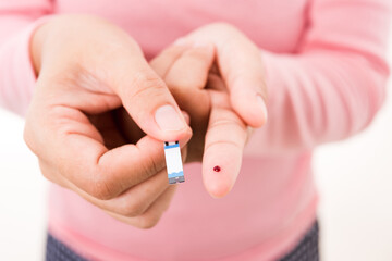 Closeup hands woman holding a plate measuring glucose test level checking with blood on a finger...