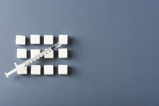 White sugar cube sweet food ingredient geometry pattern and syringe tube, studio shot isolated on a gray background, Minimal health high blood risk of diabetes and calorie intake concept
