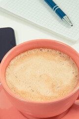 Mobile phone, coffee with milk and notepad for writing notes. White background