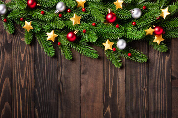 Christmas holiday garland border, Top view flat lay of tree fir branches, and Xmas ornament bauble decor and the stars on black table wood background with copy space, Happy new year day concept