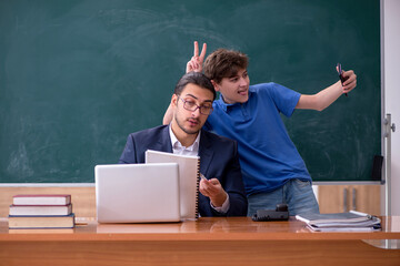 Young male teacher and schoolboy in the classroom