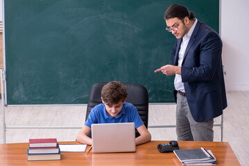 Young male teacher and schoolboy in the classroom