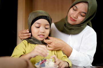 Muslim mother teaching her daughter how to wear a Hijab. 