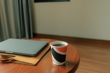 Paper cup of hot drink and laptop on the table. Concept of work from home.