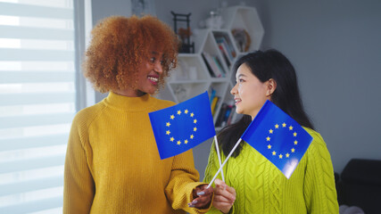Multiracial friendship and equality. African american and asian woman holding european union flag....