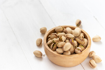Pistachio nuts in a wooden bowl on white background