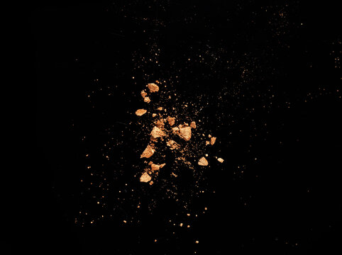 Texture of gold eye shadow isolated on black background. Macro texture of broken gold powder
