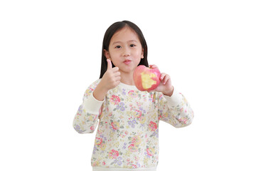 Asian little kid girl holding fresh red apple and doing ok sign, thumb up with fingers over white with clipping path. Focus at child face