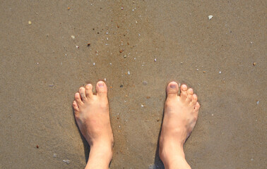 Closeup feet on the sand beach. Above view