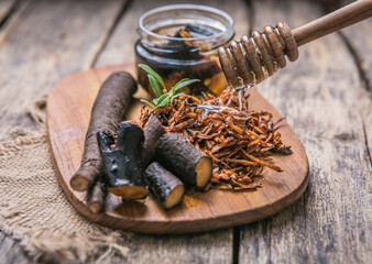 Comfrey root ( Symphytum)  on a table with honey collected in spring, on a table - obrazy, fototapety, plakaty
