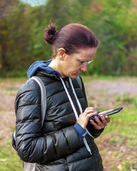 A female outdoor uses a smartphone.