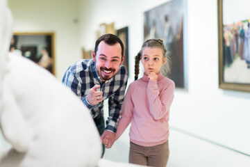 glad father and daughter regarding paintings in halls of museum