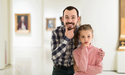 young european father and daughter looking at paintings in halls of museum