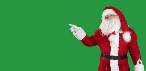 santa claus on a green background stands points a finger at an empty space for the text. Copy space.