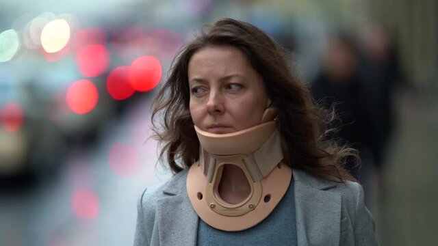portrait of an adult woman with a medical neck brace to treat a neck injury, modern lifestyle, she walks on the street in the city against the background of a highway.