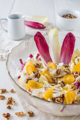 Chicory salad with orange and walnuts on white background, vertical