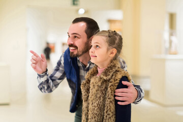 happy spanish father and daughter looking at paintings in halls of museum