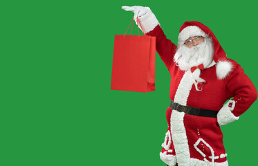 santa claus on a green background holds a red shopping bag raises it. Copy space.