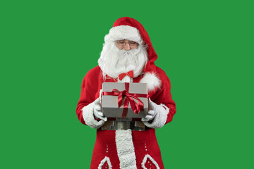 santa claus on a green background holding a box wrapped in craft paper. Red ribbon and bow. Copy space.