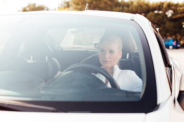 Beautiful female blonde driver behind the wheel of a sports car