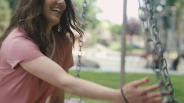 Close-up of a young mother pushing her young son in a swing at the park