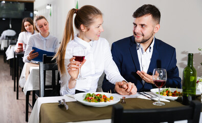 Fototapeta na wymiar Elegant female and her boyfriend are celebrating date for dinner in luxury restaurante indoor.