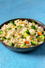 Vegan stir fied rice with vegetables, a close-up in a pan on a blue background