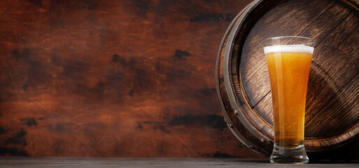 Glass of light lager beer and old wooden barrel
