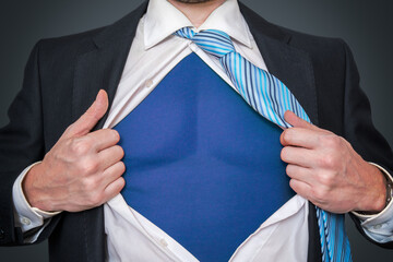 Strong businessman as superhero is opening his shirt.
