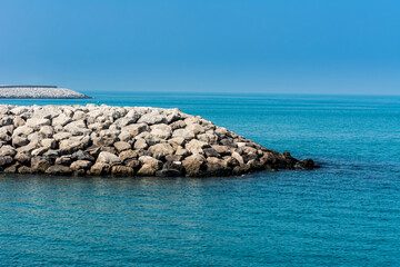 Blue sea and stone dam in the Persian Gulf  in the Corniche park in the Abu Dhabi, United Arab Emirates.