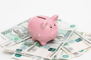 Pig piggy bank stands on paper banknotes, Russian rubles. Saving money, financial problems. The photo