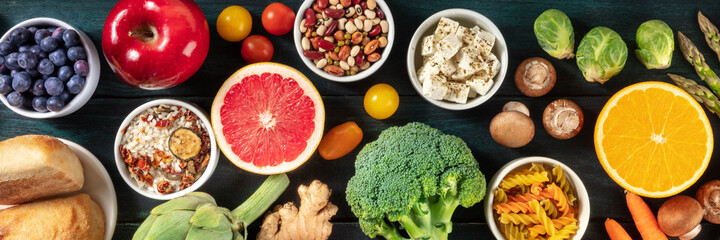 Vegetarian food panorama. Healthy organic products, shot from the top on a dark background, a flat...