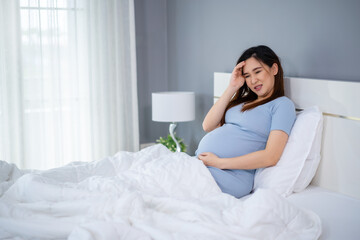 stressed pregnant woman has a headache on bed