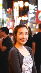 Portrait of Young Lady looking at the camera  in the City with crowd people. Caucasian woman walking the streets of the city with lots of people at night.