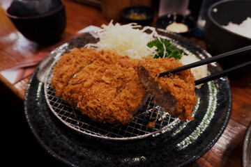 Close up to the Japanese famous meal tonkatsu mixed with pork and beef deep fried cutlet with freshness served with sides cabbage salad for dinner in the restaurant
