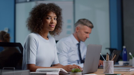 Mixed race businesswoman using laptop. Female executive turning head to camera