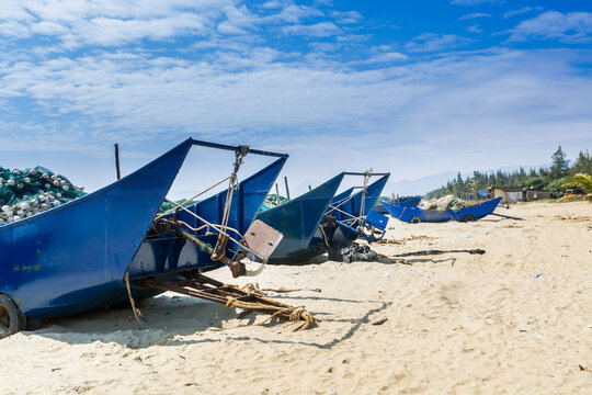 Blue fishing boat on the sand beach against blue and white cloudy sky in Yangxi, Yangjiang, Guangdong, China.