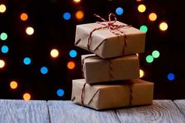 Christmas or New Year gift boxes on a wooden surface against a background of colorful lights....